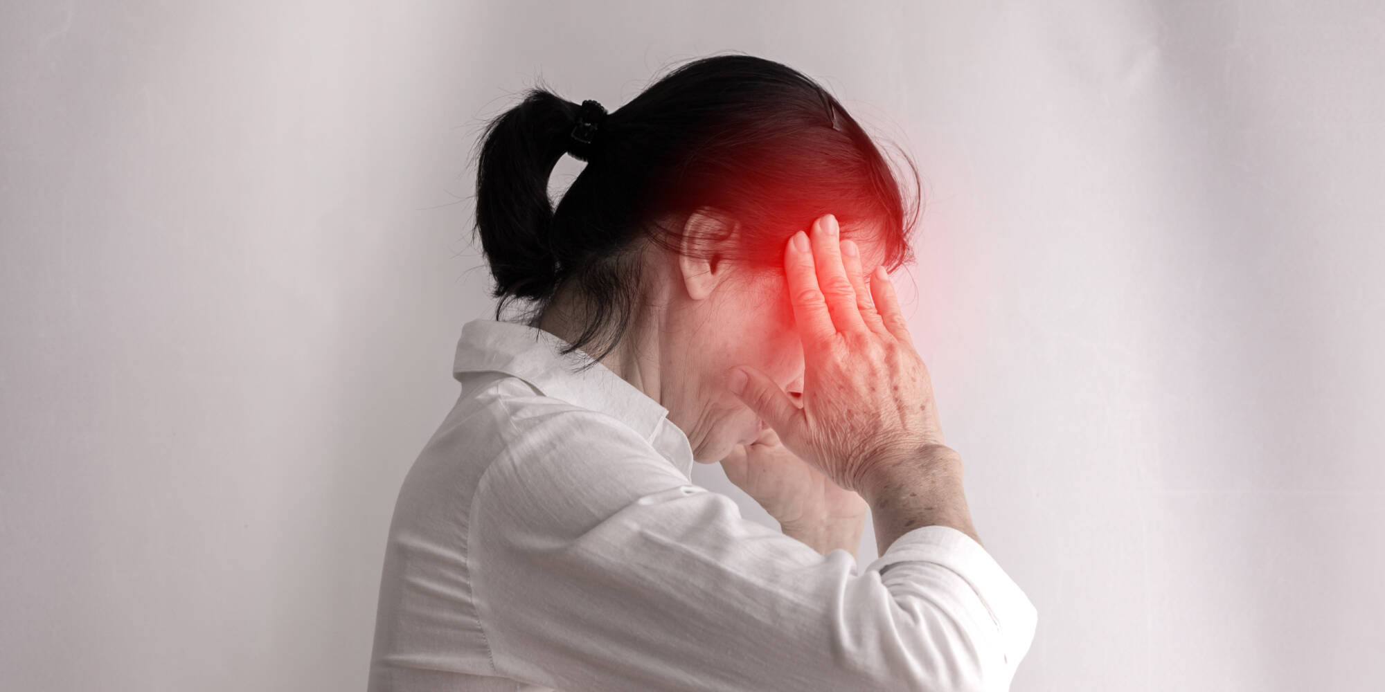 頭痛で悩む中年女性の顔